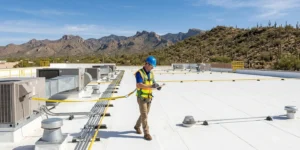 Professional contractor inspecting a commercial roofing system on a flat roof in Tucson, Arizona